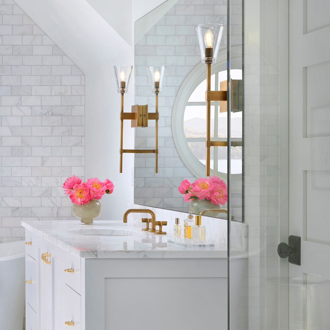 Gold and glass sconces in white bathroom